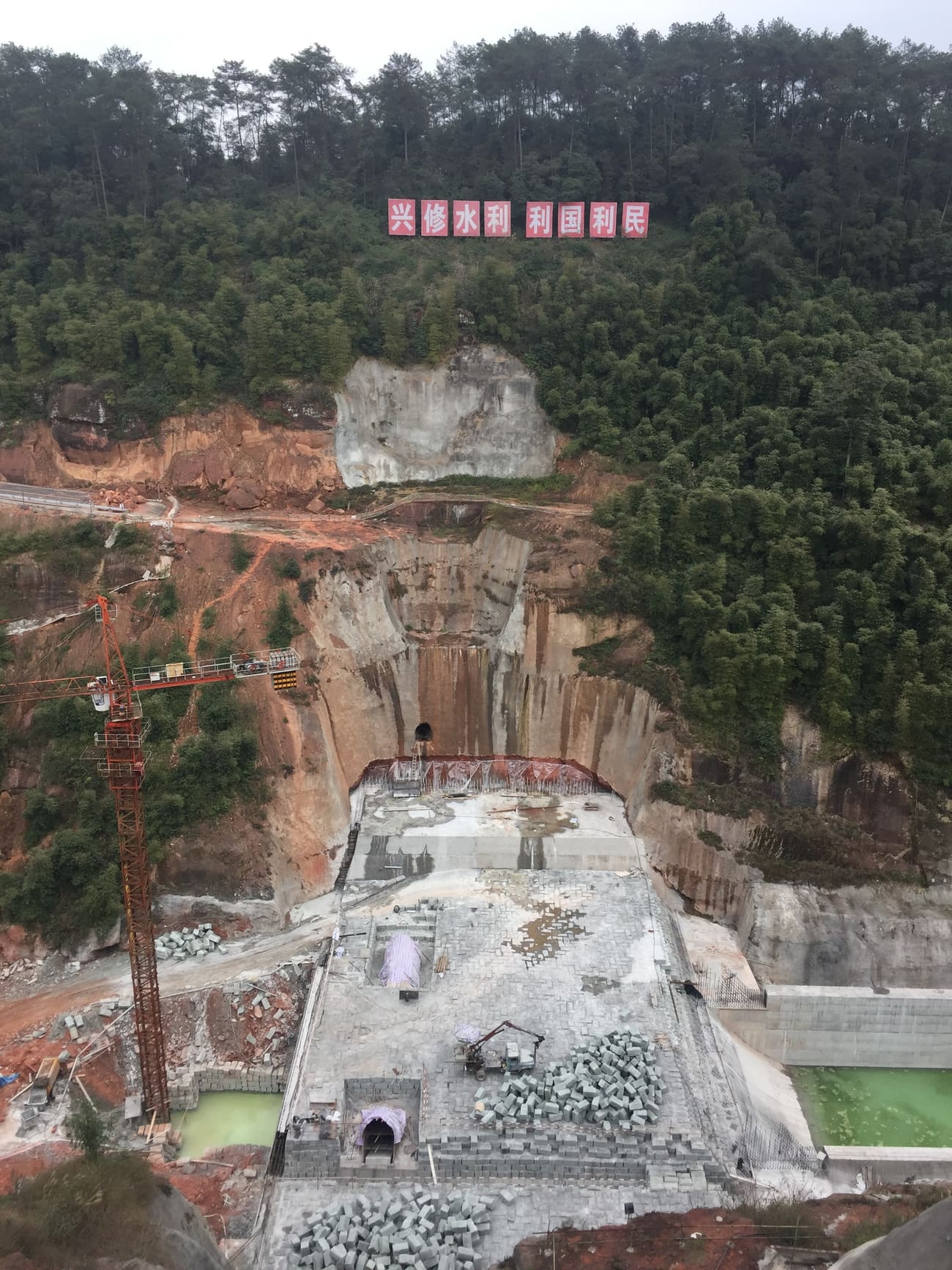 丘陵间在建的水库,标语写着“兴修水利 利国利民”