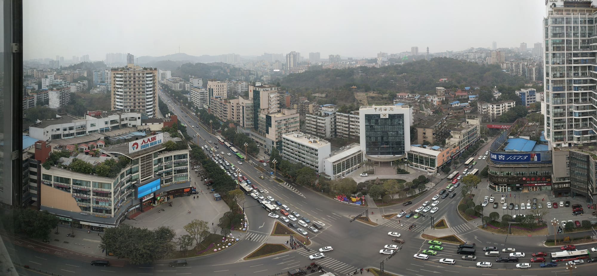 市街从釜溪河谷向丘陵展开，旧城、厂区与高层住宅叠在同一幅地景中。